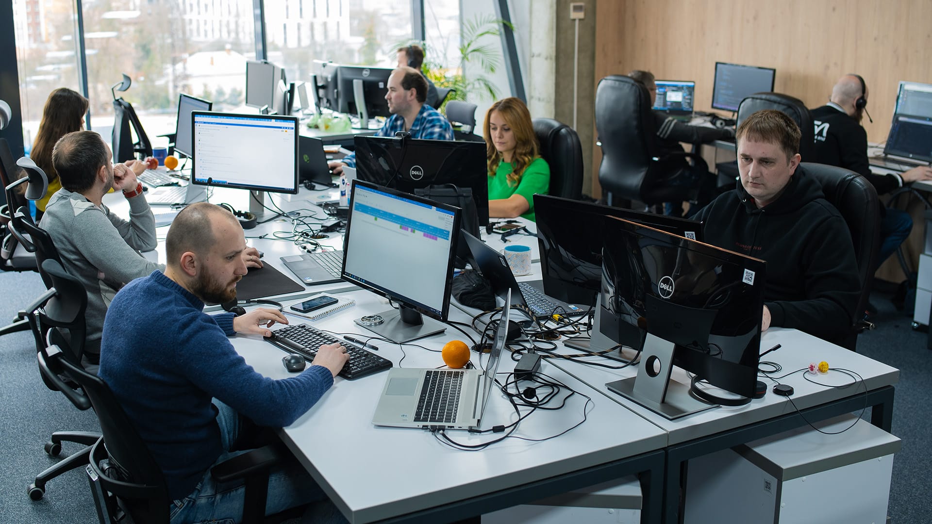 A team of focused IT professionals working at multi-monitor setups in a well-lit, modern office environment, indicative of Conscensia's robust nearshoring services.